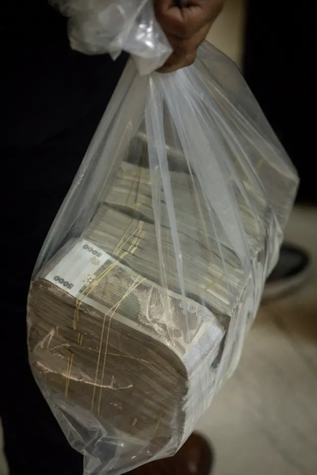 رجل يحمل كيساً من الليرات السورية بعد استبدال الدولار الأمريكي في مصرف سوريا المركزي في 24 كانون الأول/كانون الأول 2024
