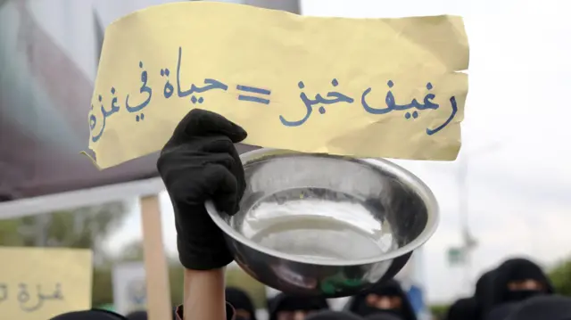 صورة لافتة ورقية صفراء كتب عليها "رغيف خبز يساوي حياة في غزة" رفعها طلاب وموظفون من جامعة صنعاء شاركوا في الاحتجاج الذي أقيم ضد استمرار القصف الإسرائيلي على قطاع غزة وحصار المساعدات إلى القطاع في 20 آب 2025 في صنعاء، اليمن.