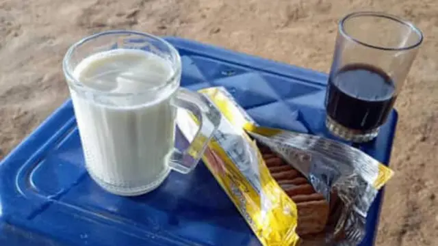 صورة تظُهر كوباً من الحليب إلى جانب كوب من الشاي وعلبة من البسكويت.