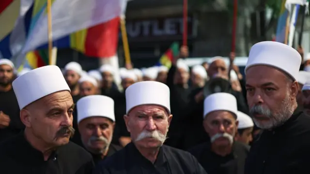رجال دين دروز يحملون لافتات خلال مظاهرة تضامنية مع المجتمع الدرزي من مدينة السويداء جنوب سوريا في 19 تموز/تموز