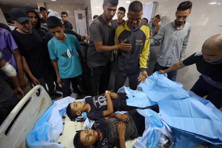 EDITORS NOTE: Graphic content / Palestinians mourn by the bodies of two children at the al-Awda hospital where casualties of Israeli fire were transported ahead of their funerals, on آب 29, 2025, in Nuseirat in the central Gaza Strip, as the war between Israel and the Hamas militant movement continues.