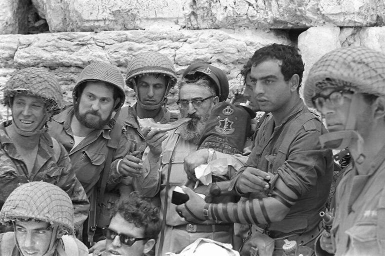 A group of soldiers surrounds then-IDF chief rabbi Shlomo Goren as he blows a shofar at the Western Wall in Jerusalem's Old City on حزيران 7, 1967. (Bamahane Magazine/Defense Ministry's IDF Archive)