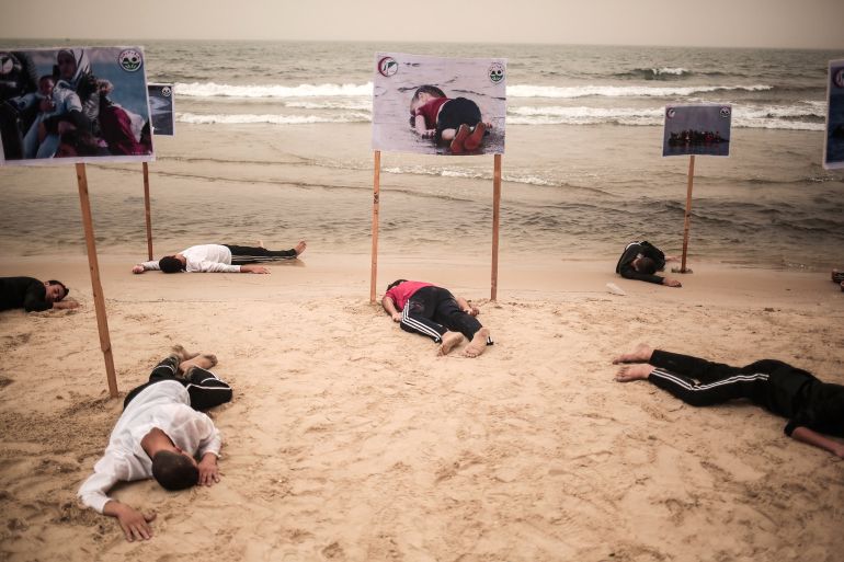 GAZA CITY, GAZA - SEPTEMBER 8: People lie on the Gaza beach to commemorate Aylan Kurdi, the three-year-old boy dressed in shorts and a red T-shirt, and 12 Syrians who drowned in the Aegean Sea after two boats filled with refugees en route to Greece sank, in Gaza City, Gaza on أيلول 8, 2015. (Photo by Mustafa Hassona/Anadolu Agency/Getty Images)