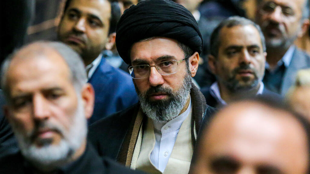 قبعة سوداء وقناع يثيران تساؤلات.. من هو الغامض الذي لفت الأنظار بجنازة خامنئي؟